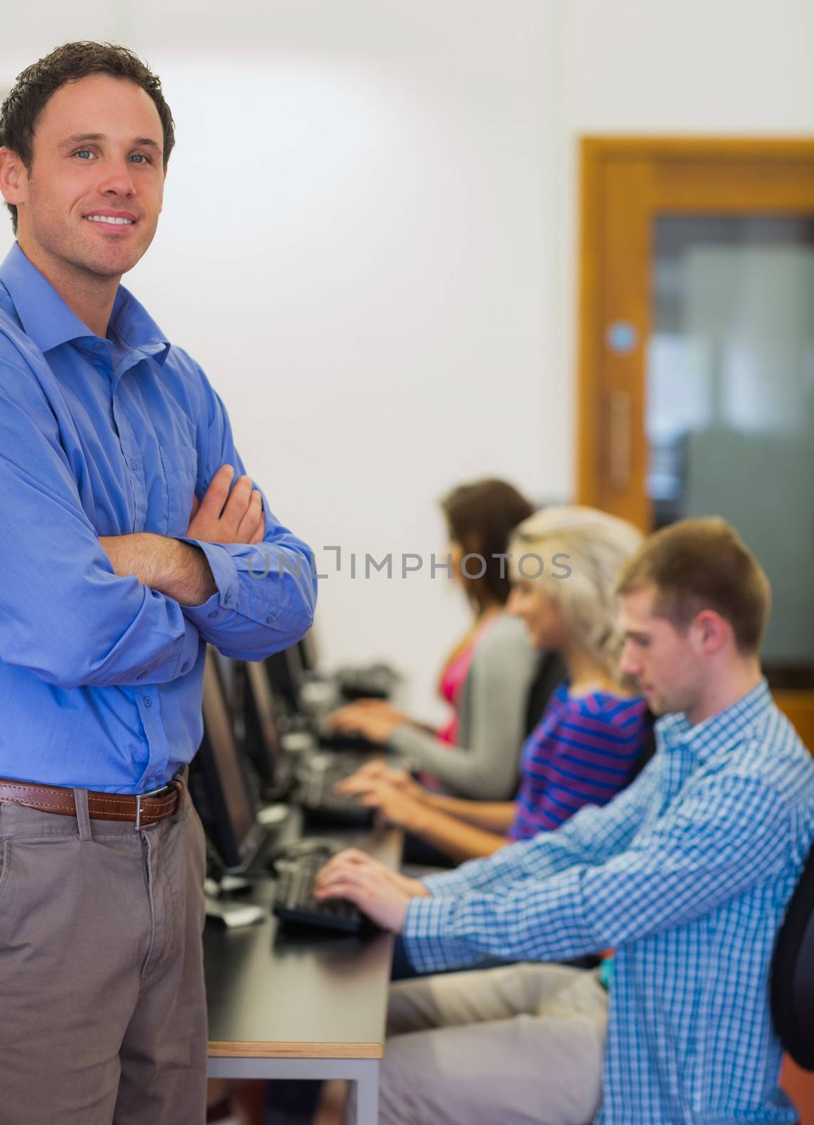 Teacher with students using computers in computer room by Wavebreakmedia