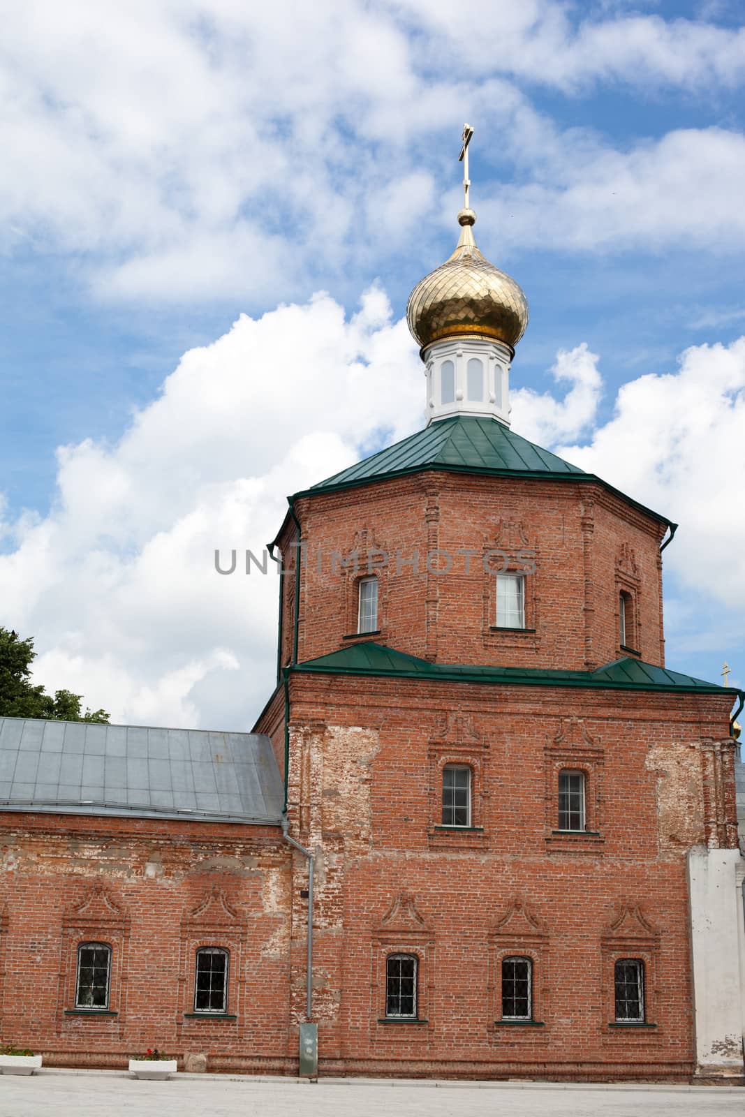 Brick red orthodox church with one golden dome
