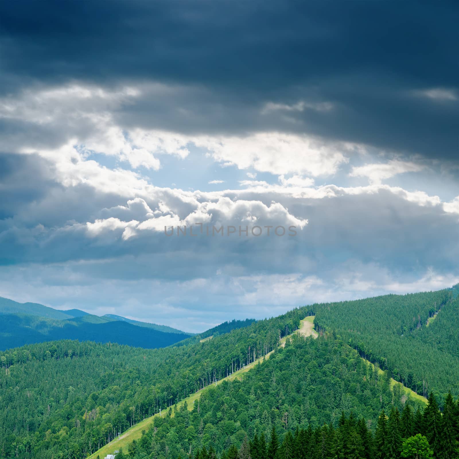 dramatic low clouds over green mountain