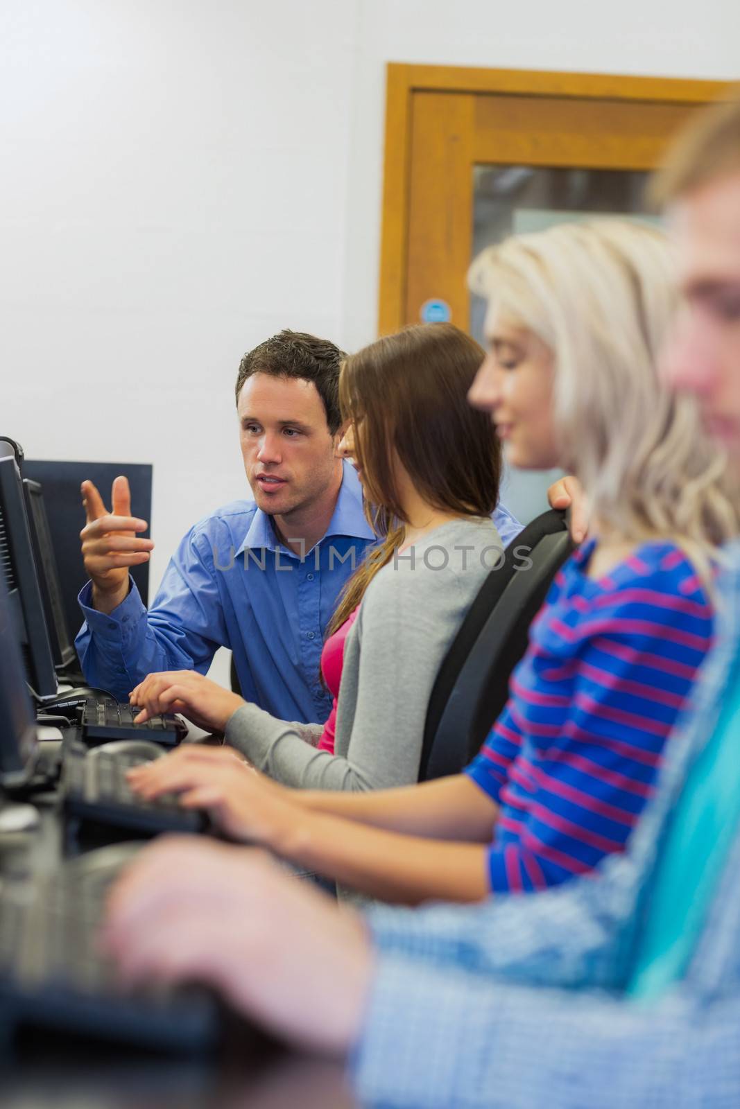 Teacher explaining to young college students in the computer room