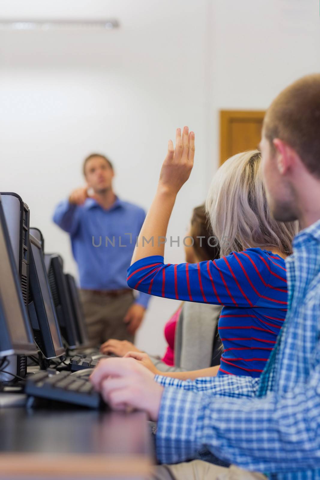 Teacher explaining to young college students in the computer room