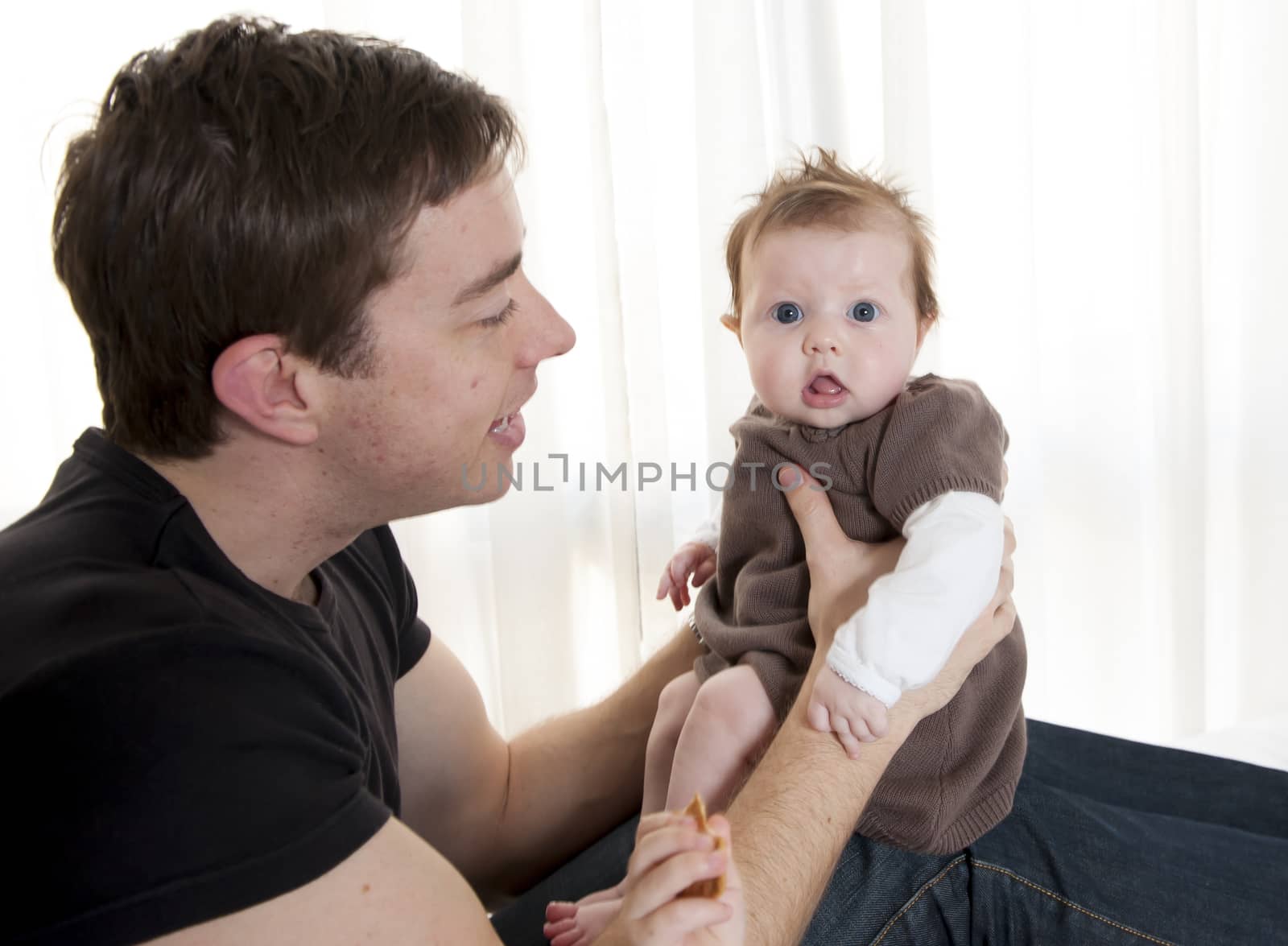 Young father holding his baby girl on surprised expression