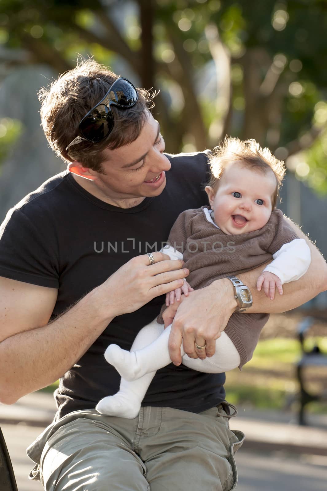 Young father playing with sweet baby girl outdoors