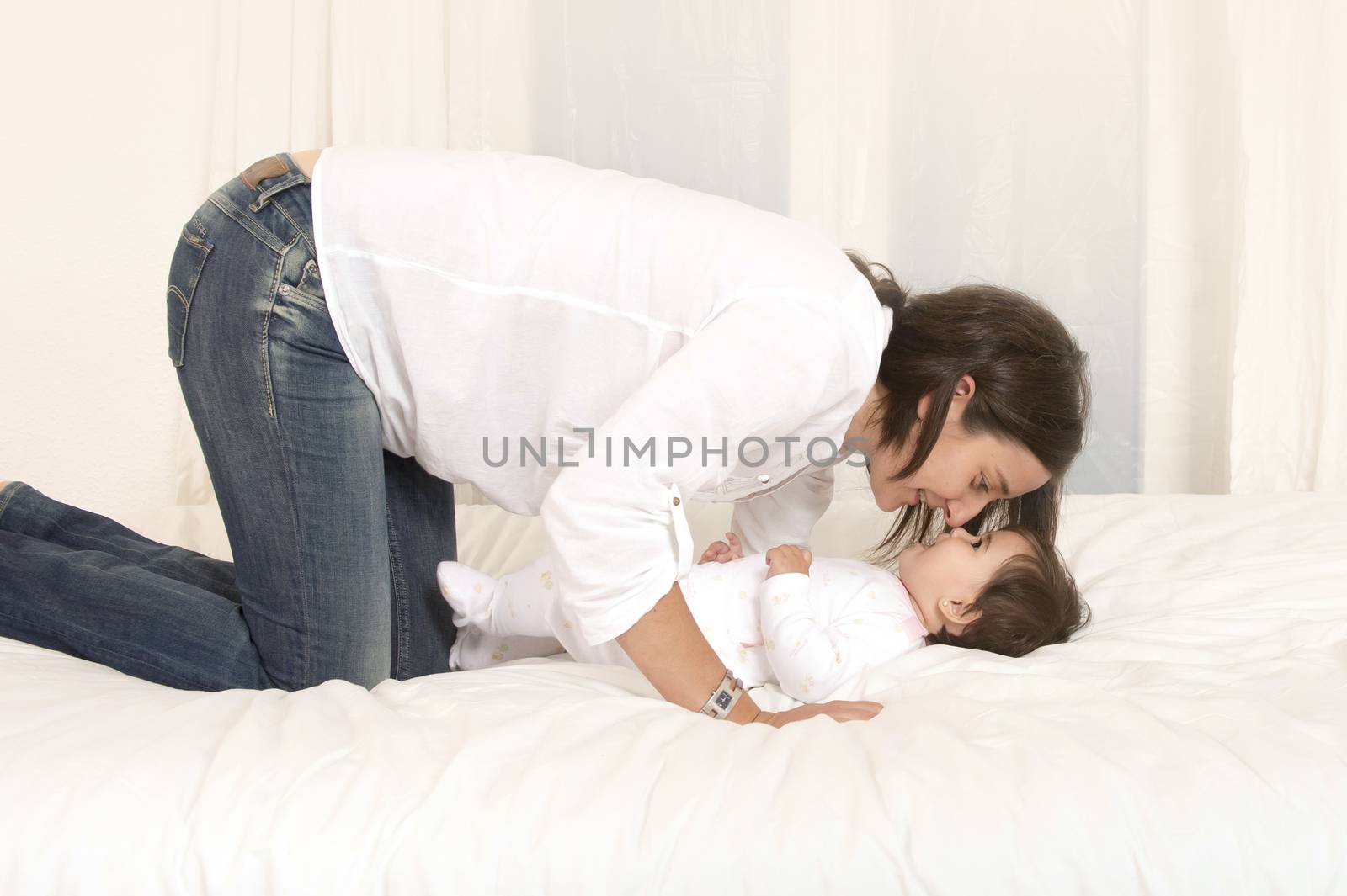 Mother and daughter playing on bed isolated by ocusfocus