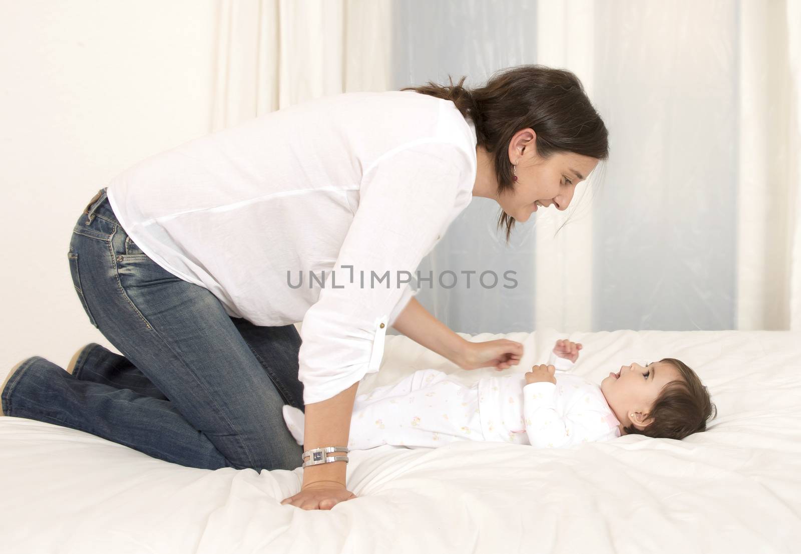 Mother and daughter playing on bed isolated on white background