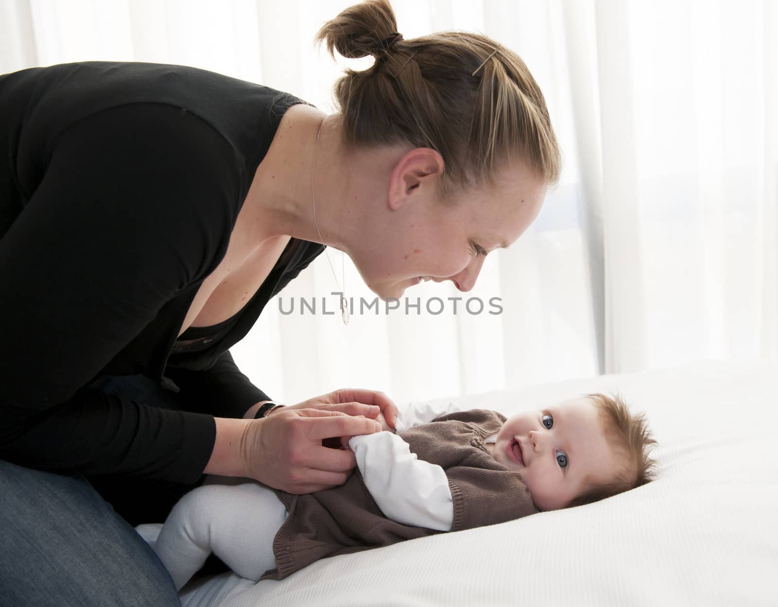 Young mother playing with sweet baby girl at home