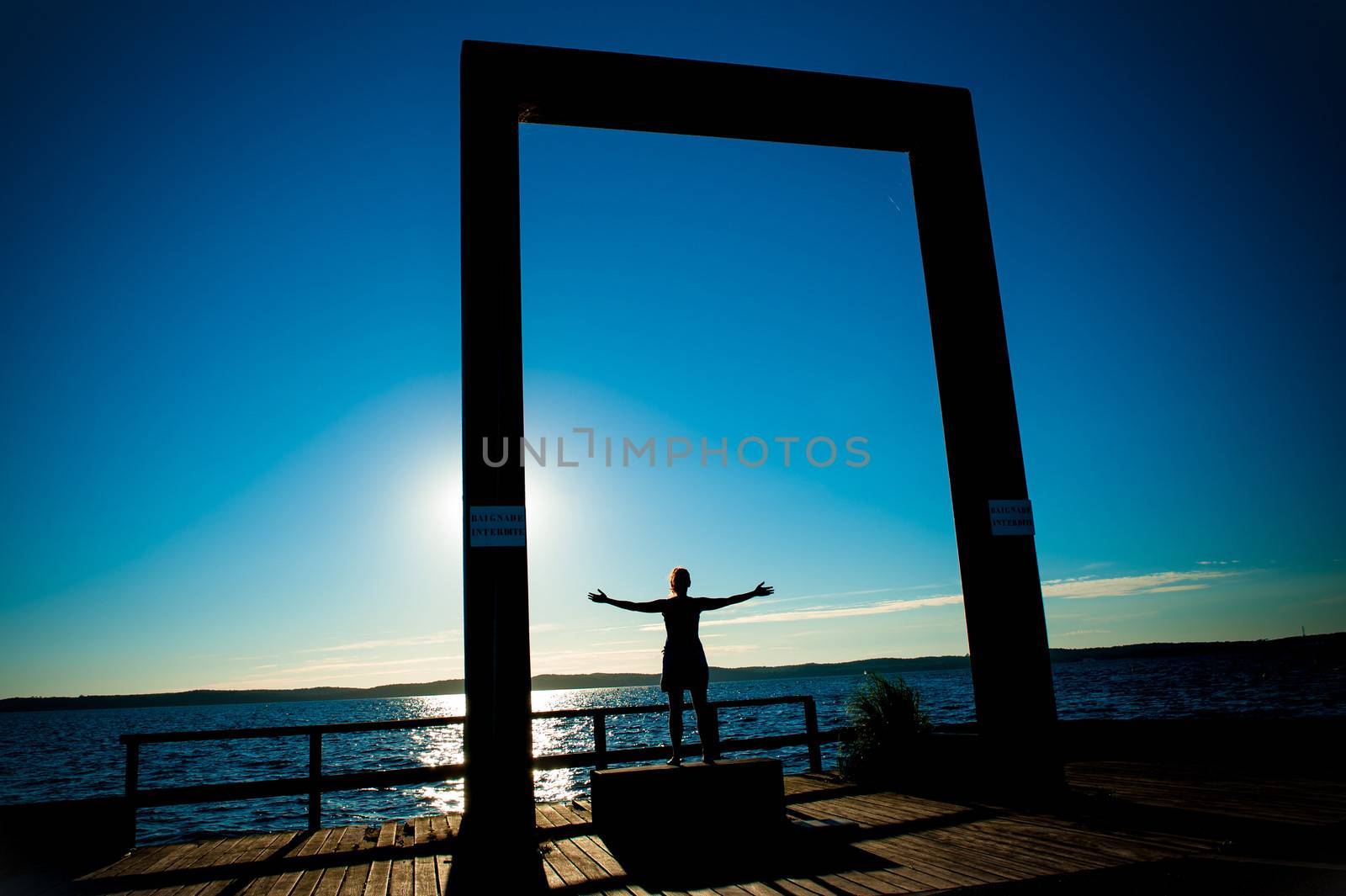 Young Woman Silhouette with open arms to the sea by ocusfocus