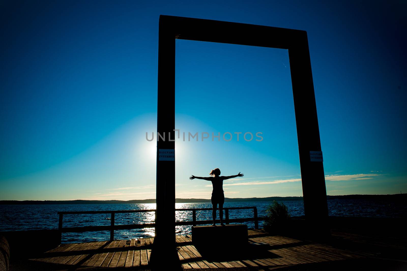 Young Woman Silhouette with open arms to the sea on Summer Sunset