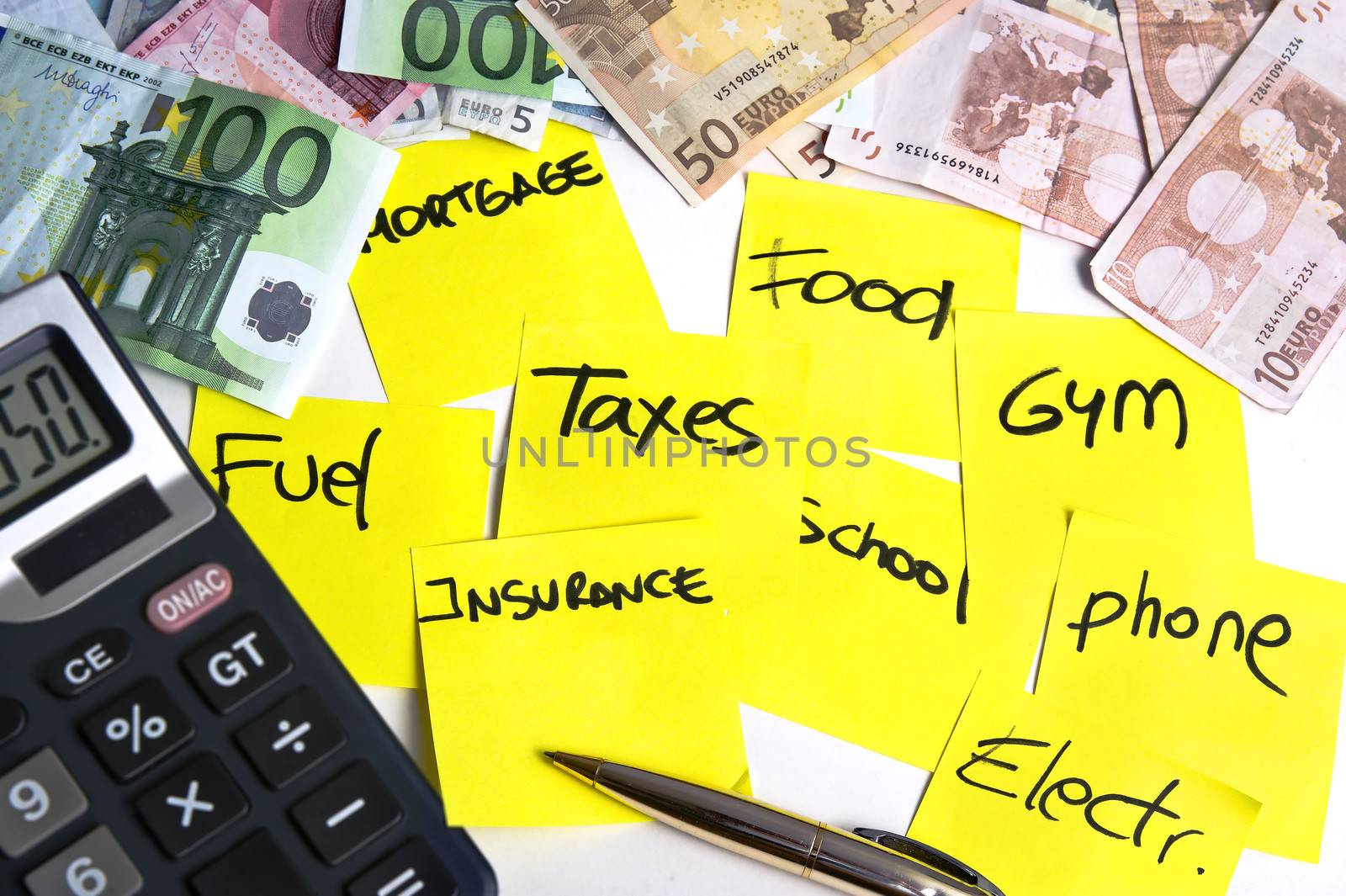 Calculator and banknotes on a table filled with yellow post it notes refering cost of living: mortgage, taxes, fuel, food, school, phone, insurance, gym and electricity