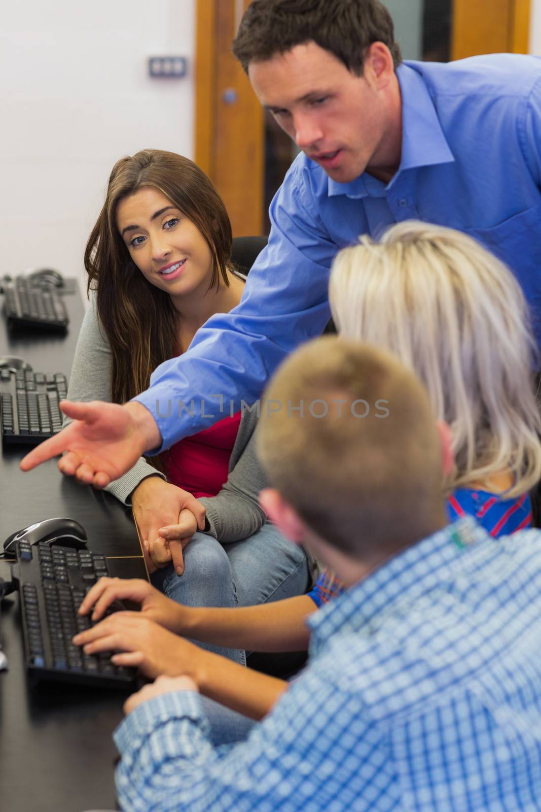 Teacher explaining to students in computer room by Wavebreakmedia