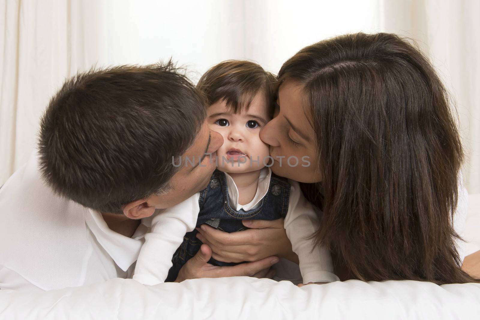 Mother and Father Kissing their Baby Girl