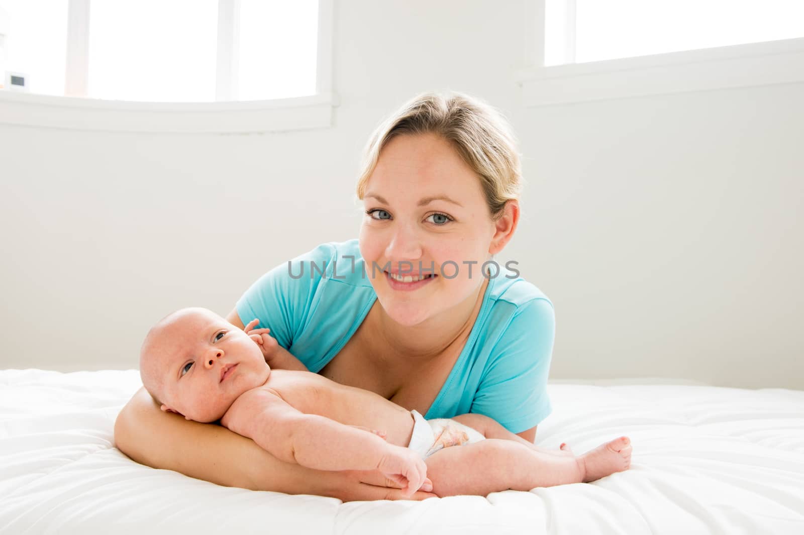 A happy Mother wearing blue shirt holding her newborn baby back lighting with white background