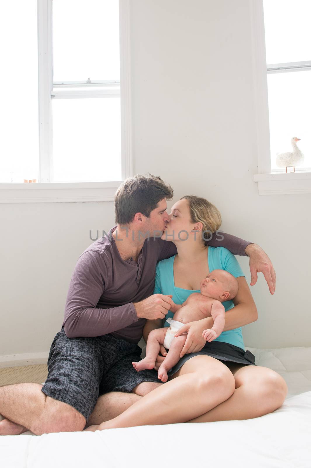 happy new parents with their newborn son kissing