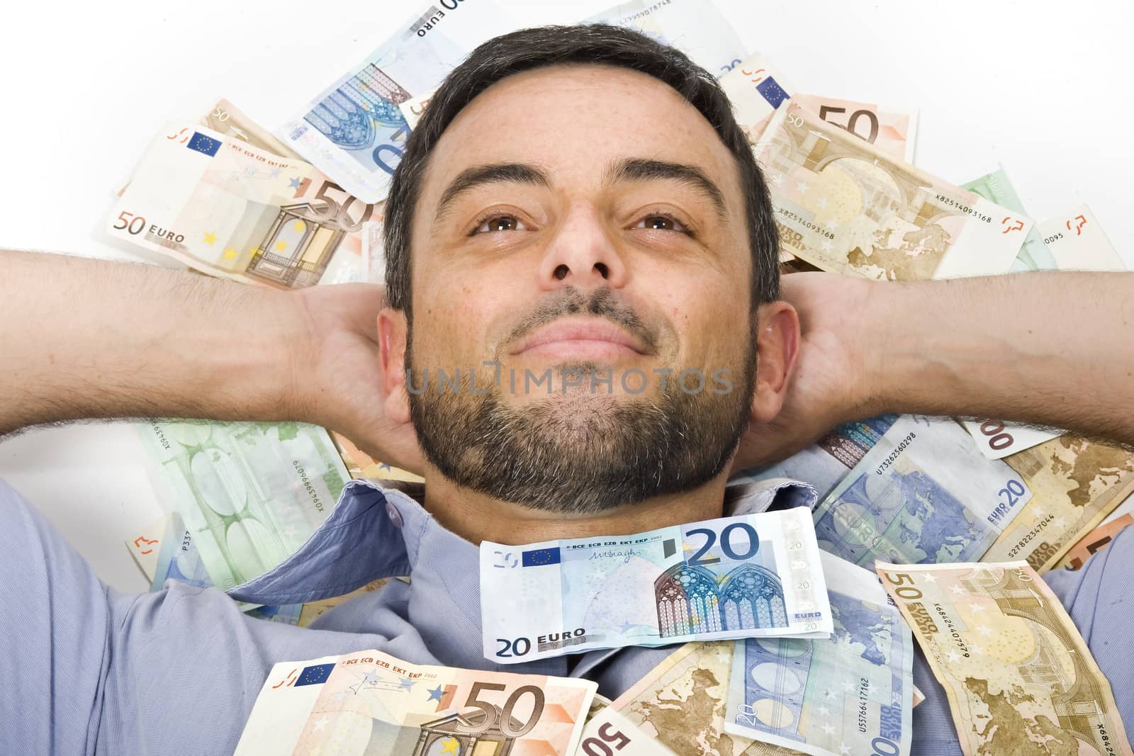Happy Young Man with Beard laying on Banknotes isolated