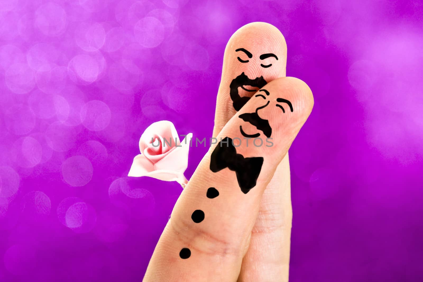 Fingers with sweet faces painted featuring a gay wedding between a man with a moustache and a bowtie and a guy with a beard an a rose