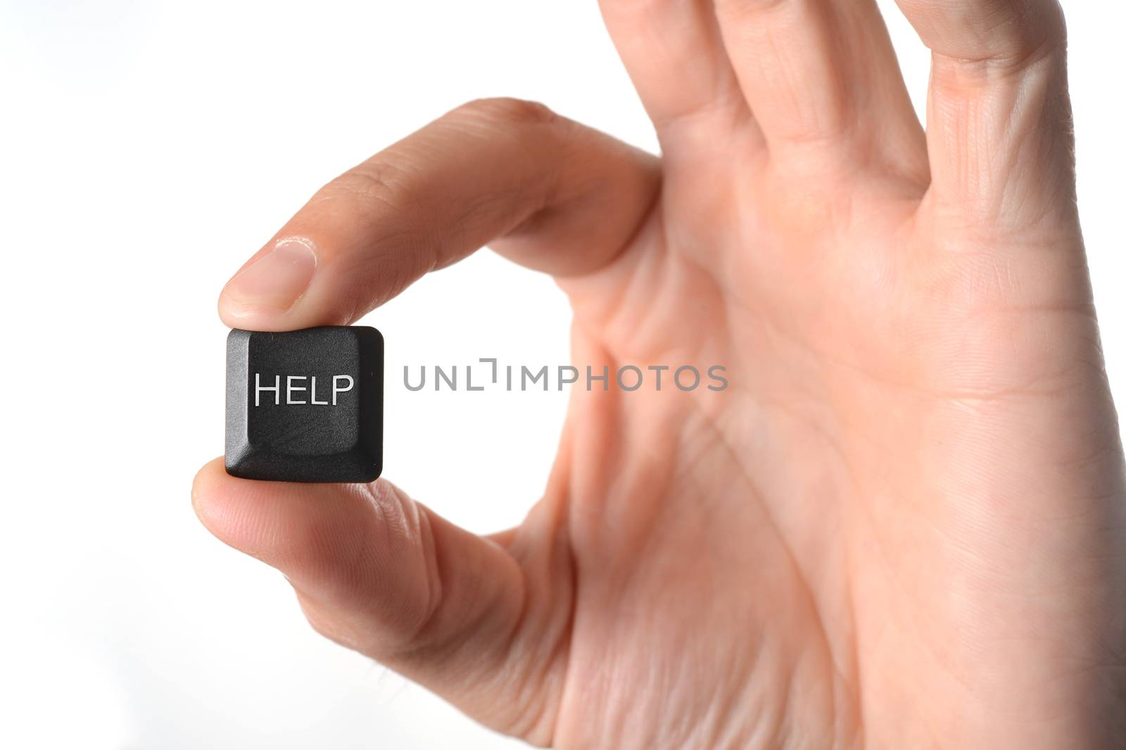 close up of a hand holding a help key from a computer keyboard on a white background