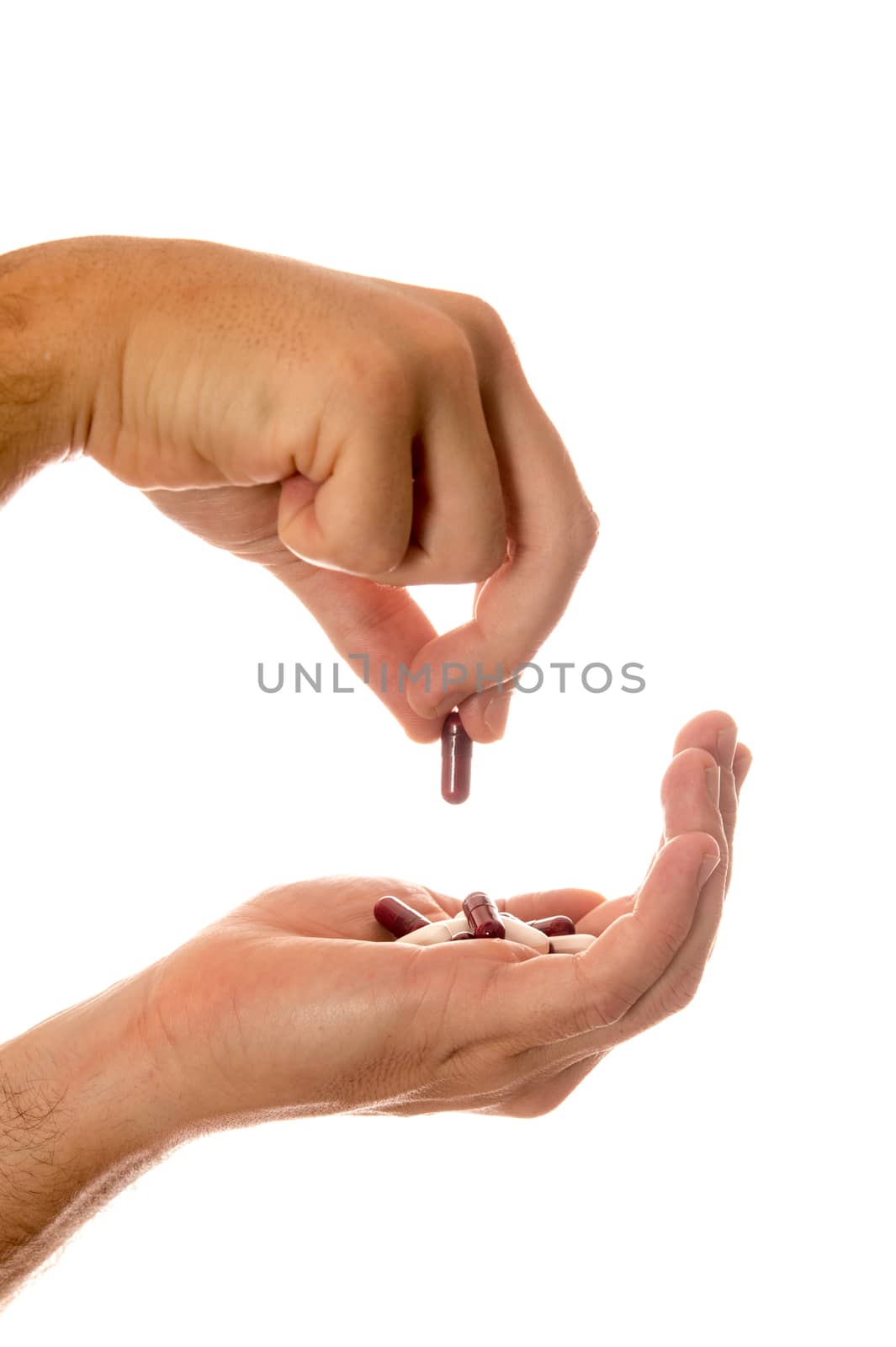 Male hand holding a handful of medical pills and picking one isolated on white background