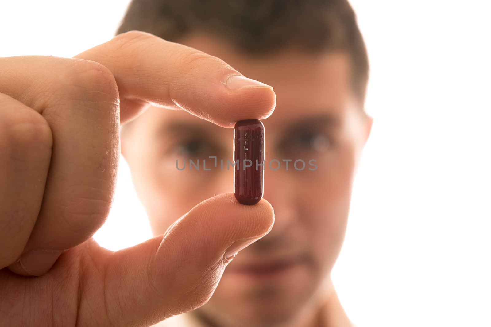 Young Man holding a Pill in his Hand isolated in White