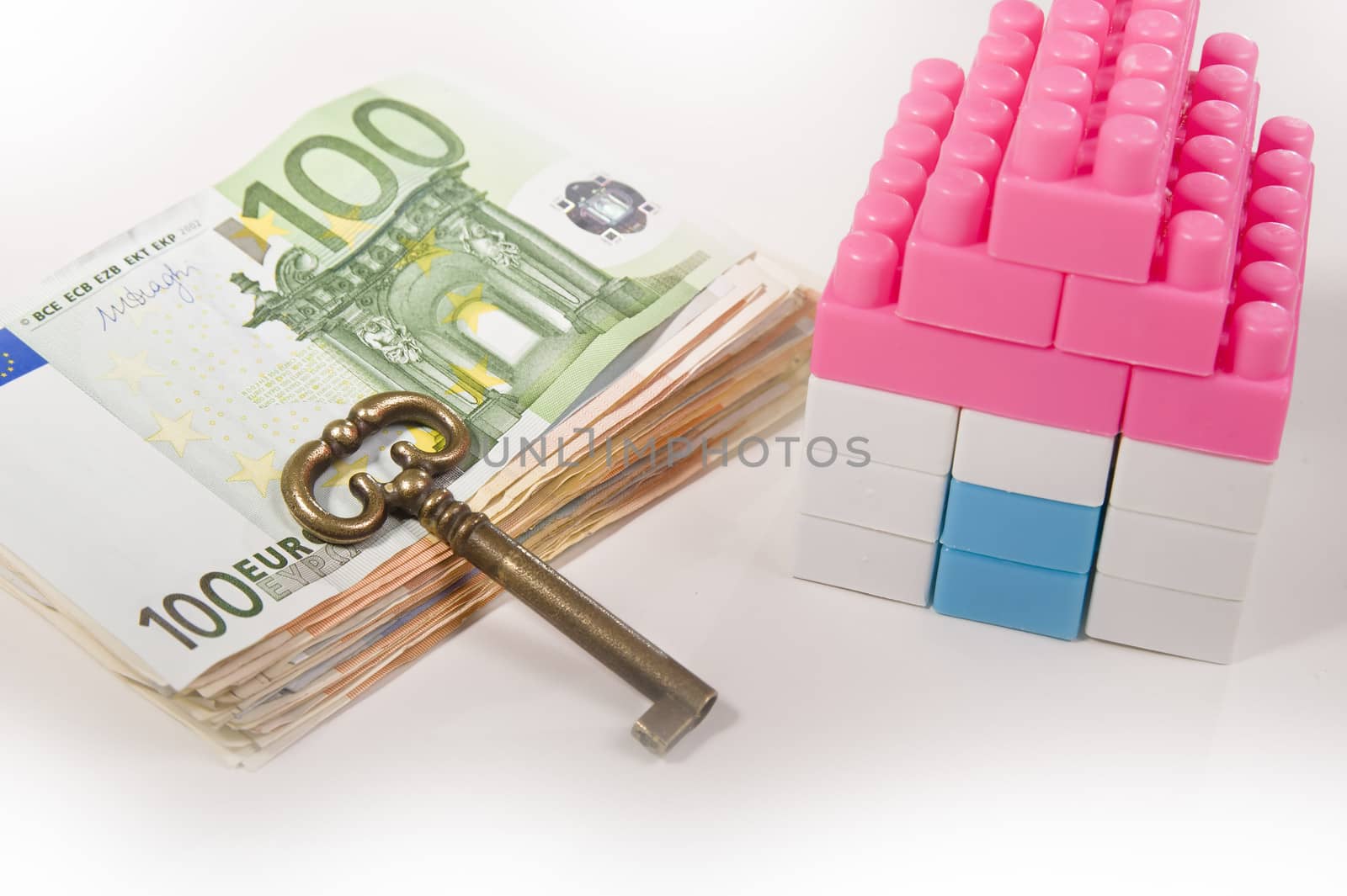  Miniature House with Key on a Banknotes Pile Isolated on White background