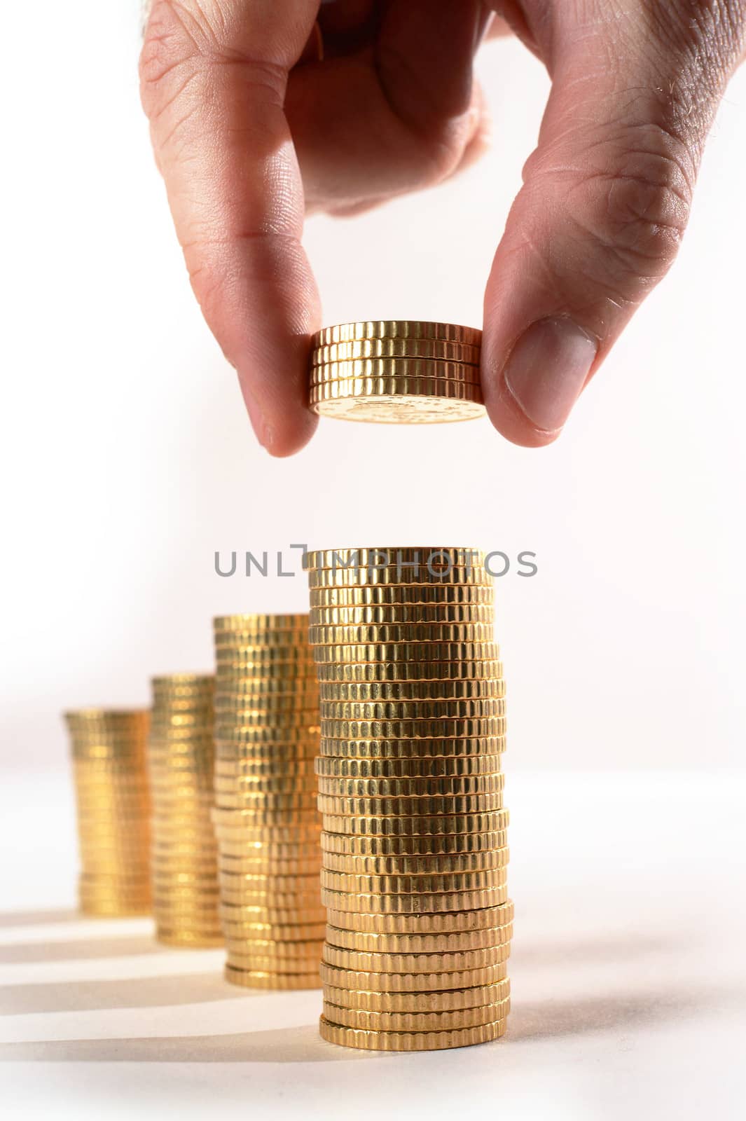 Male hand picking Euro Coins piled in stacks isolated on white background