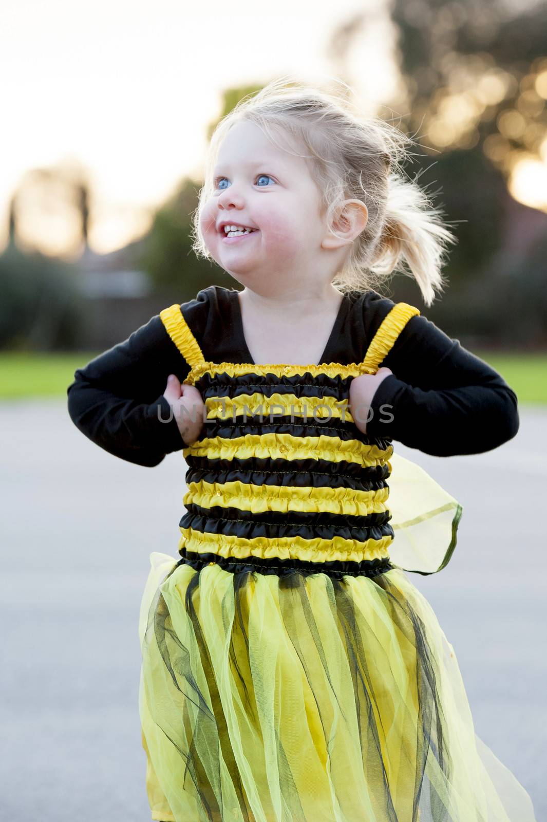 Little blond girl in bee costume dancing outdoors by ocusfocus