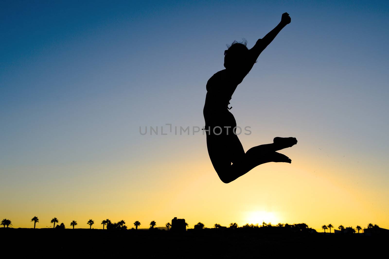 Woman Silhouette Jumping on the Beach at Sunset transmitting a concept of health, joy and freedom