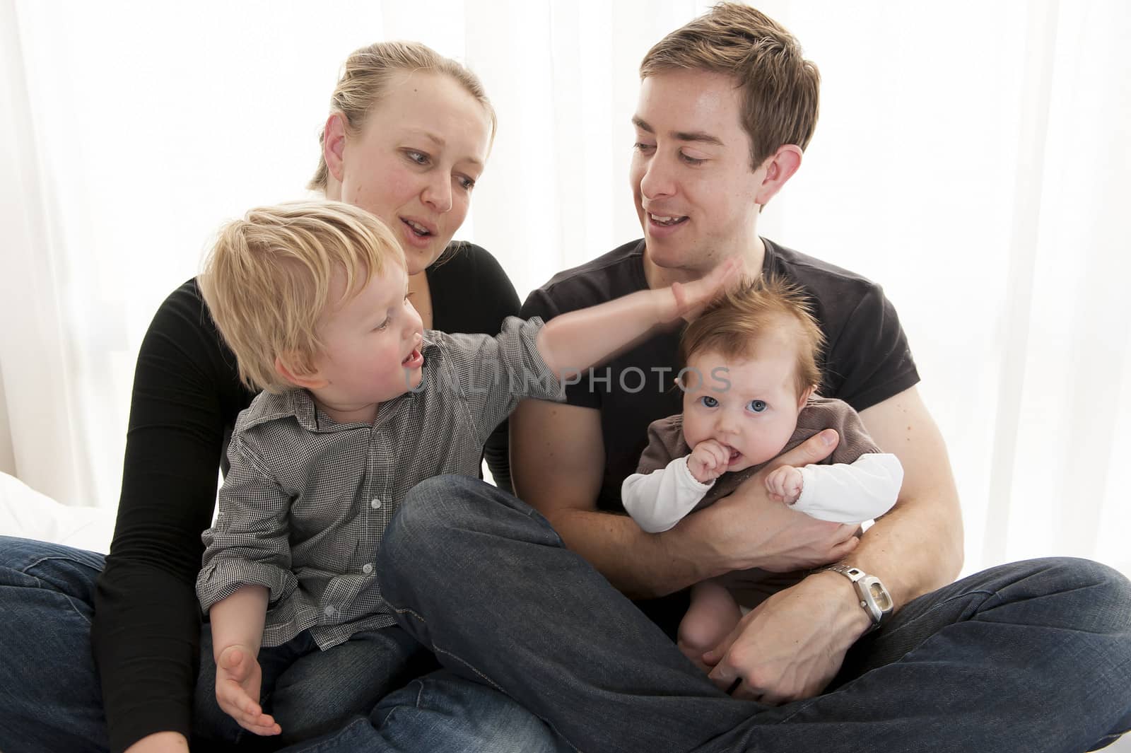 Young couple playing with baby girl and little child sitting