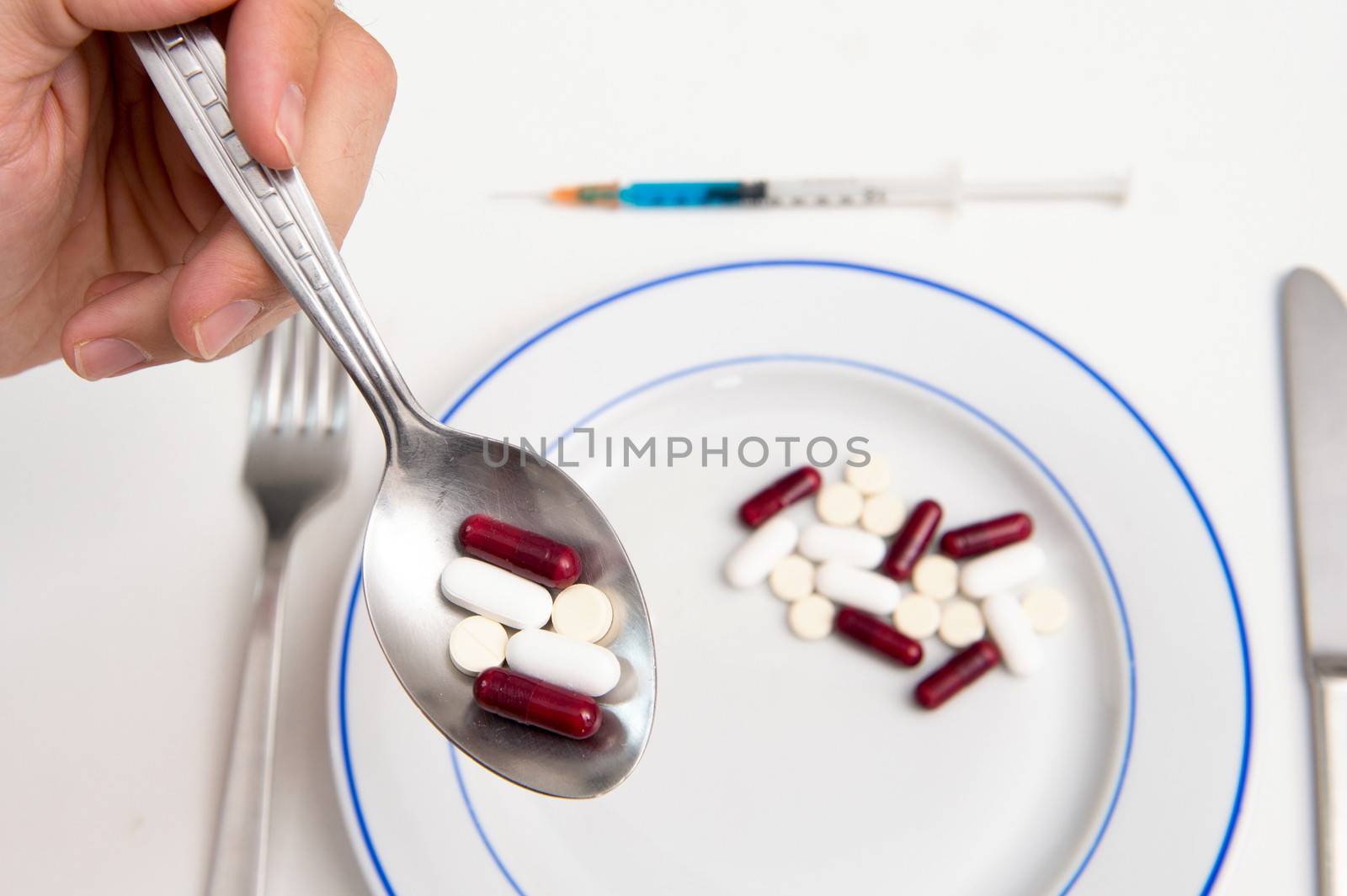 Medical Meal, Male hand holding Spoon eating Tablets and Pills on a plate