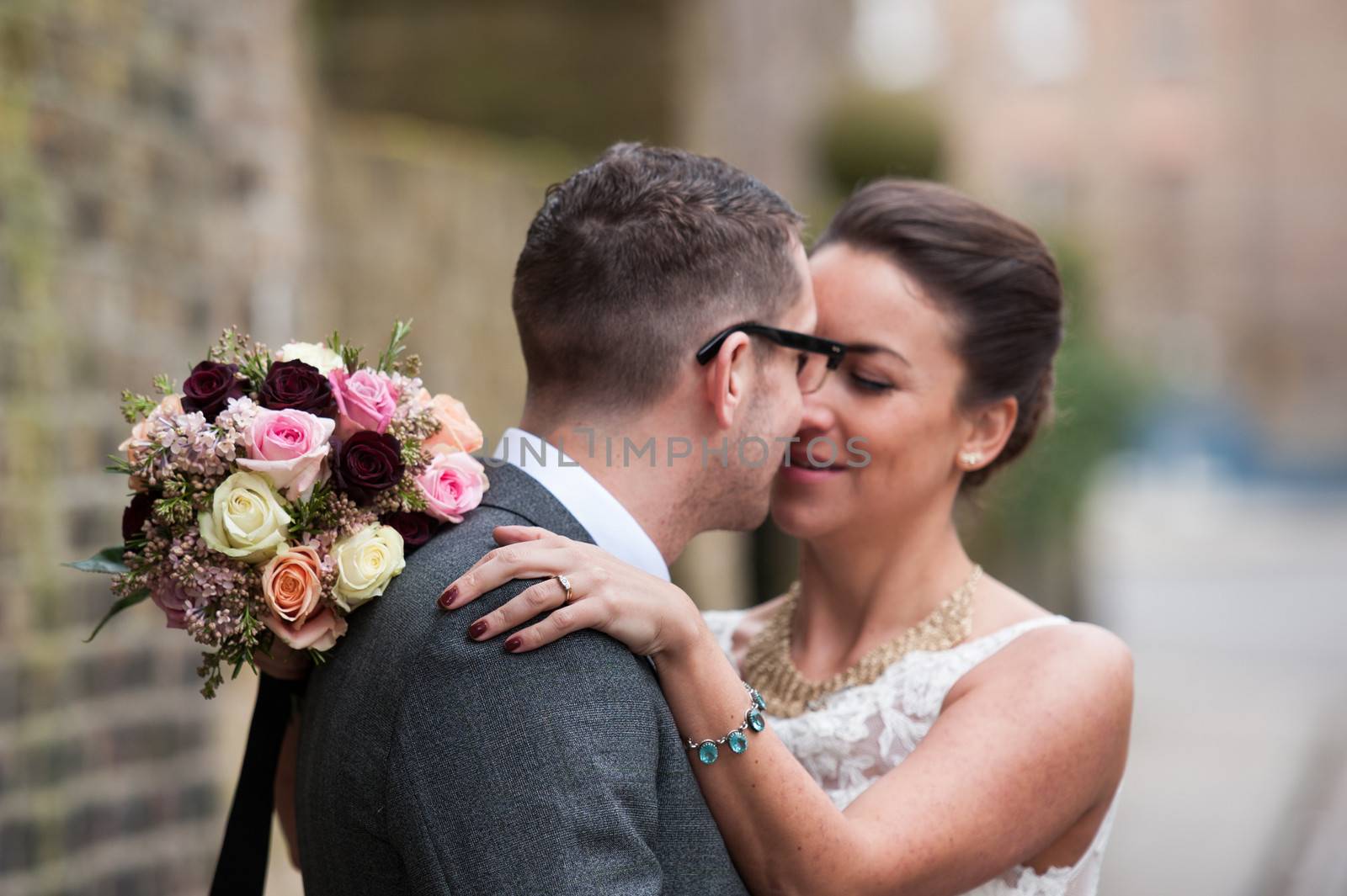 close up of wedding ring as Bride and Groom kiss