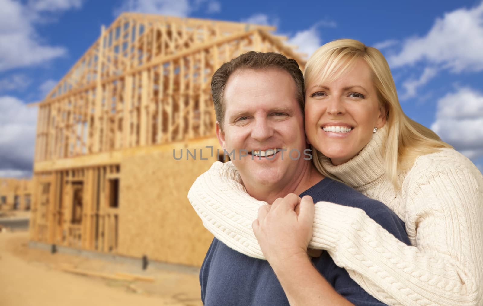 Happy Excited Couple in Front of Their New Home Construction Framing Site.