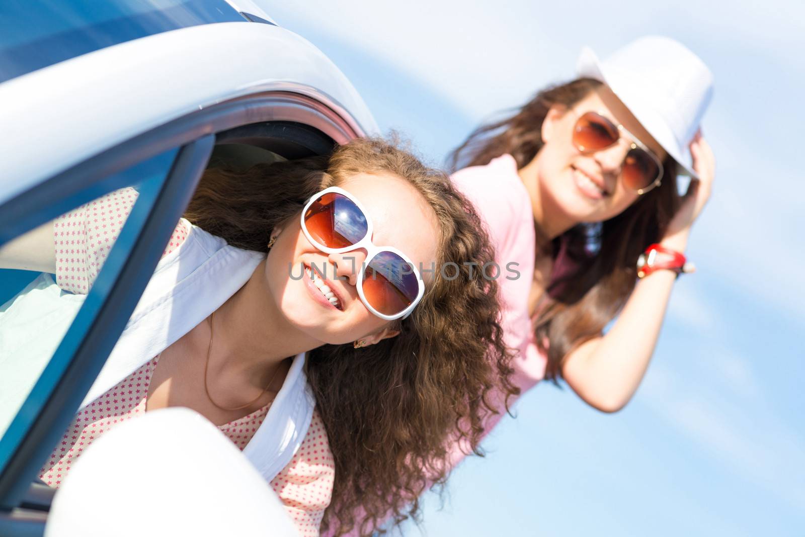 young attractive woman in sunglasses got out of the car window and laugh