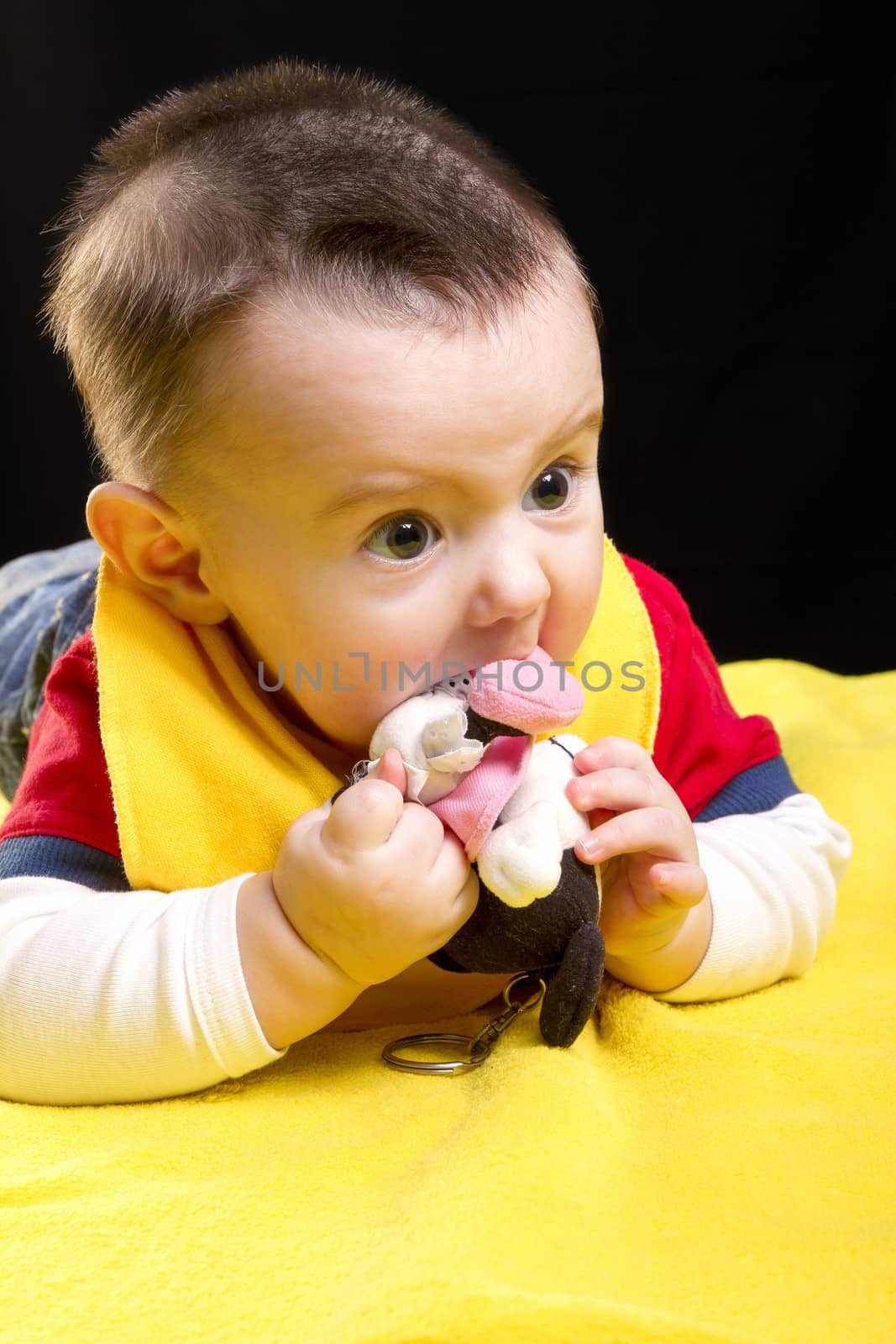 Baby boy with toy on yellow blanket 