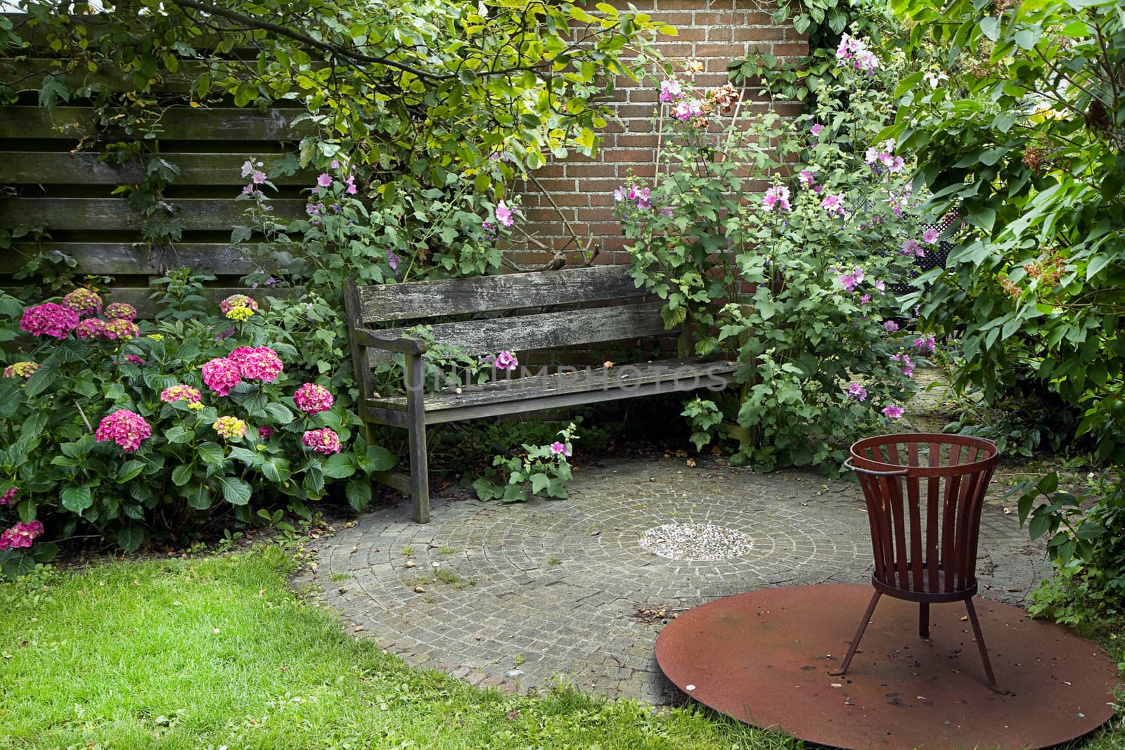 Country-style garden with bench, fireplace and lots of flowers in summer