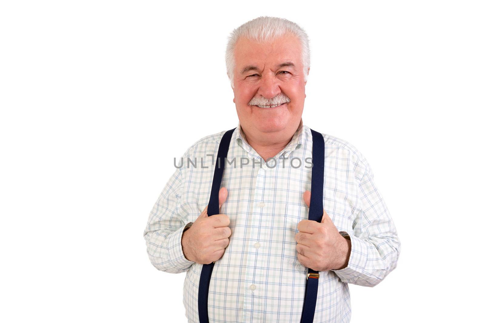 Confident senior grey-haired man with a moustache and beaming friendly smile holding his suspenders or braces, upper body isolated on white