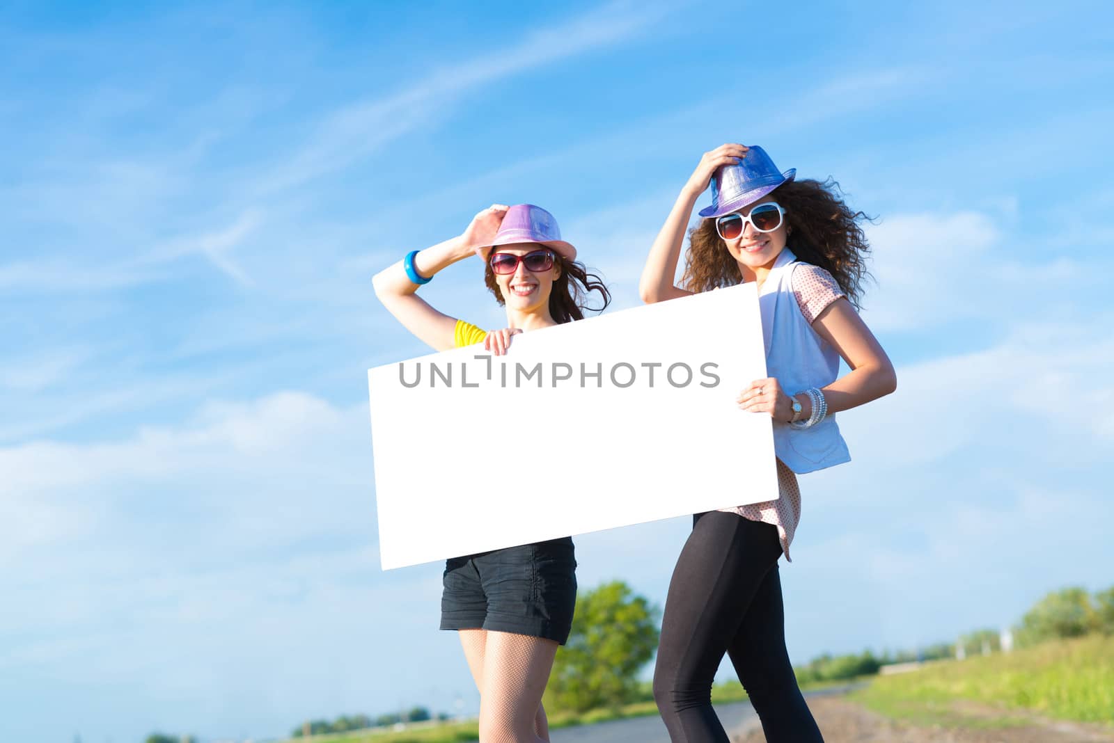 Two young women stand with a blank banner by adam121
