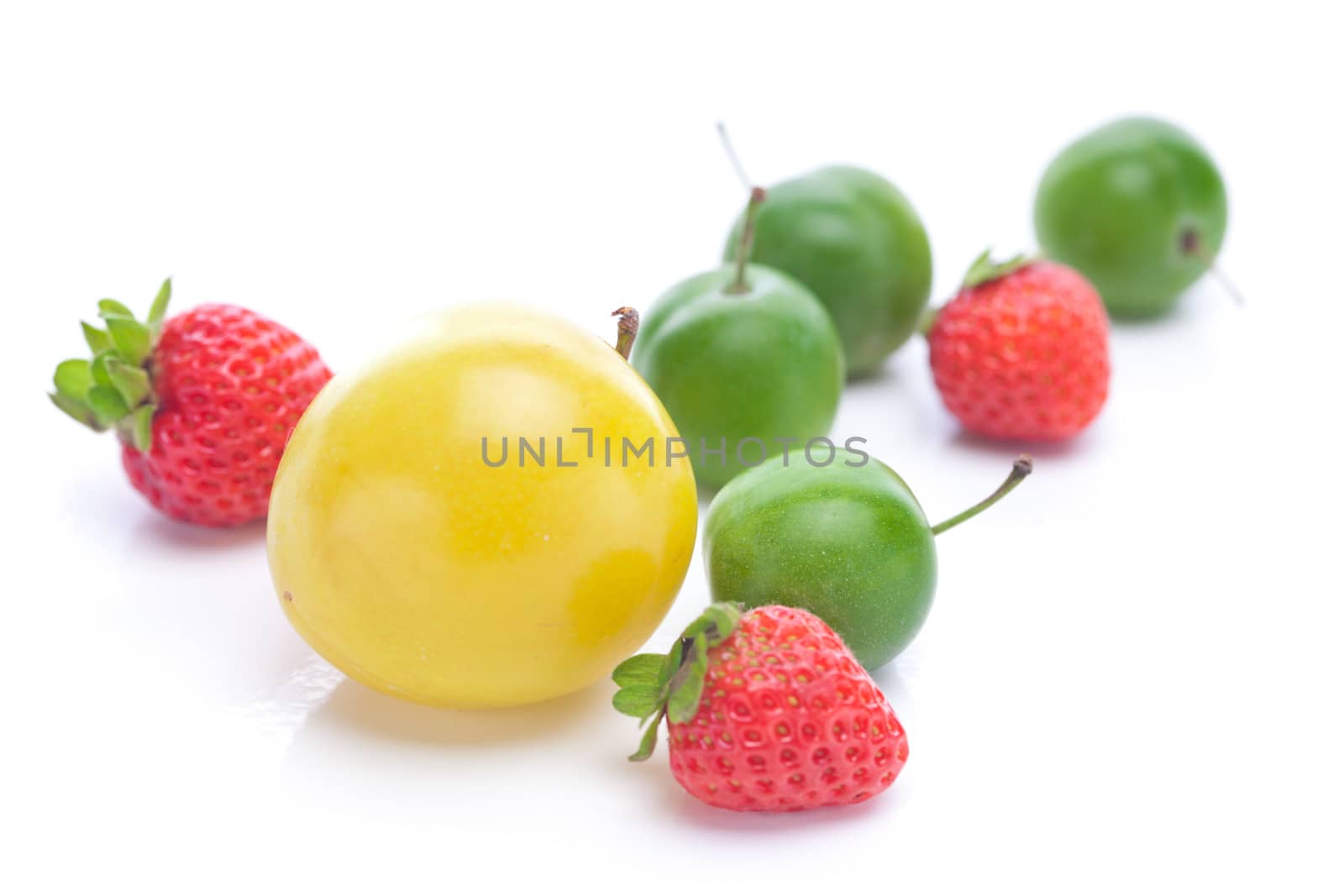 green and yellow plums and strawberries isolated on white by jannyjus