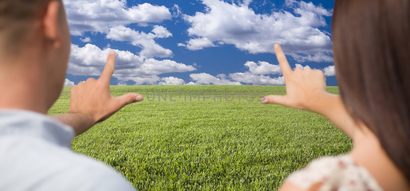 Couple Framing Hands Around Space in Grass Field by Feverpitched