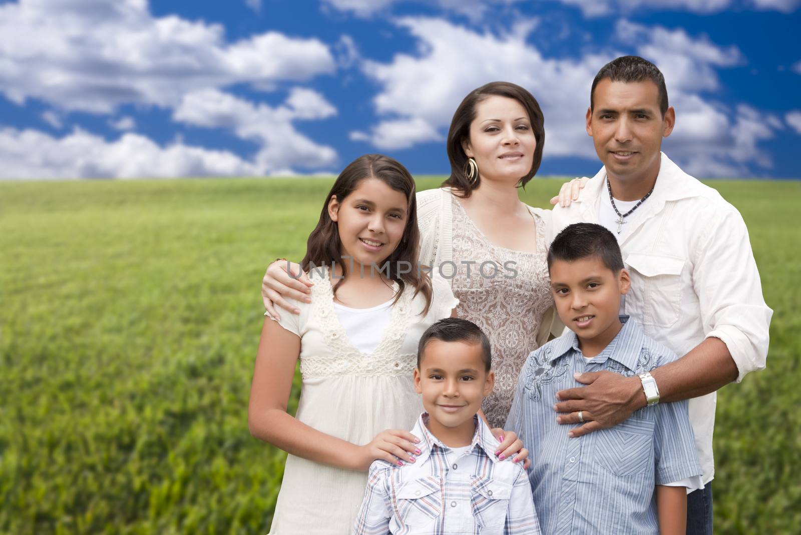 Happy Hispanic Family Portrait Standing in Grass Field.