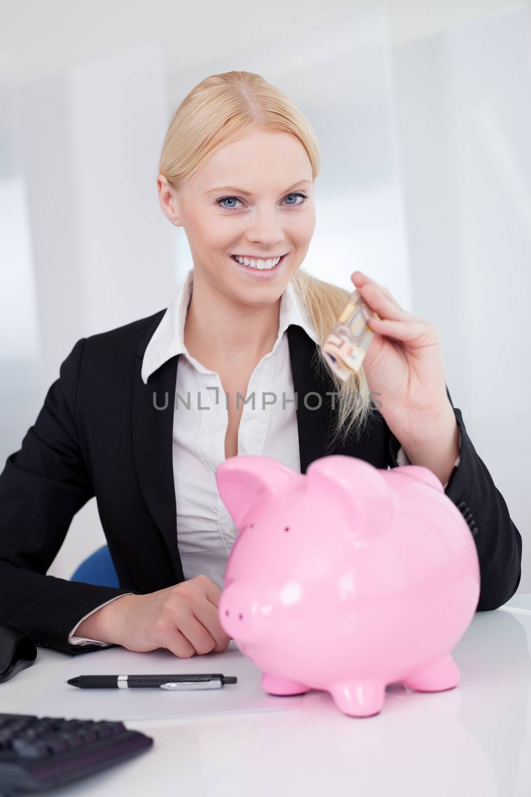 Businesswoman holding euro currency and piggybank in the office