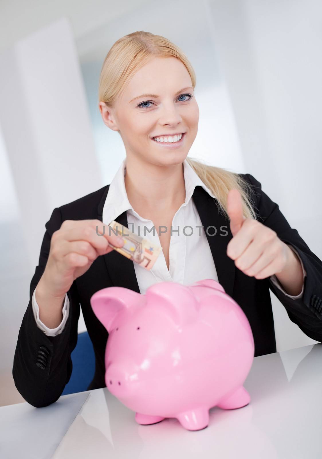 Businesswoman holding euro currency and piggybank in the office