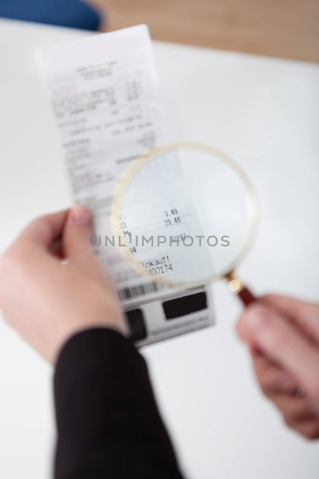 Close-up of businesswoman looking at check trough the loupe