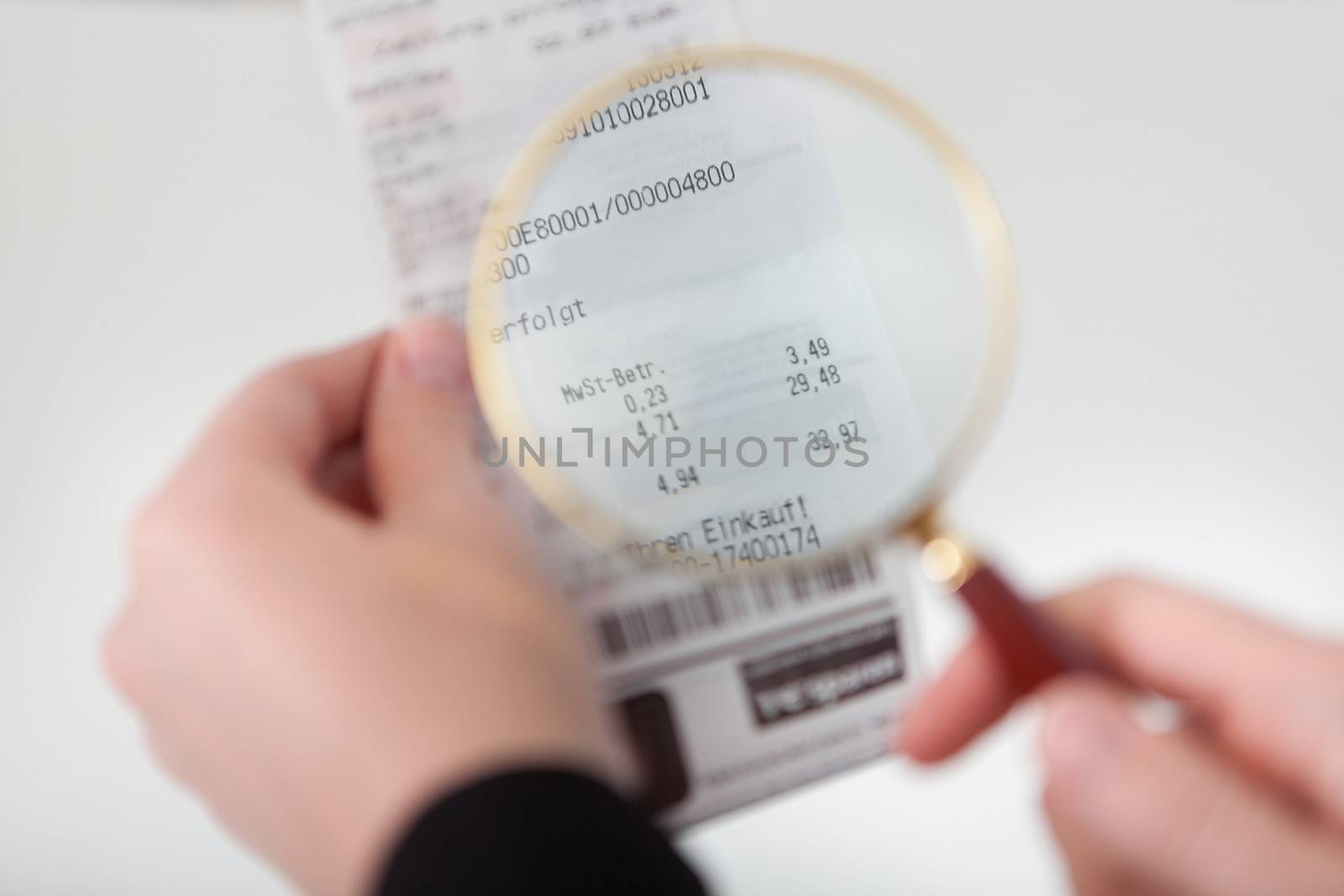 Close-up of businesswoman looking at check trough the loupe