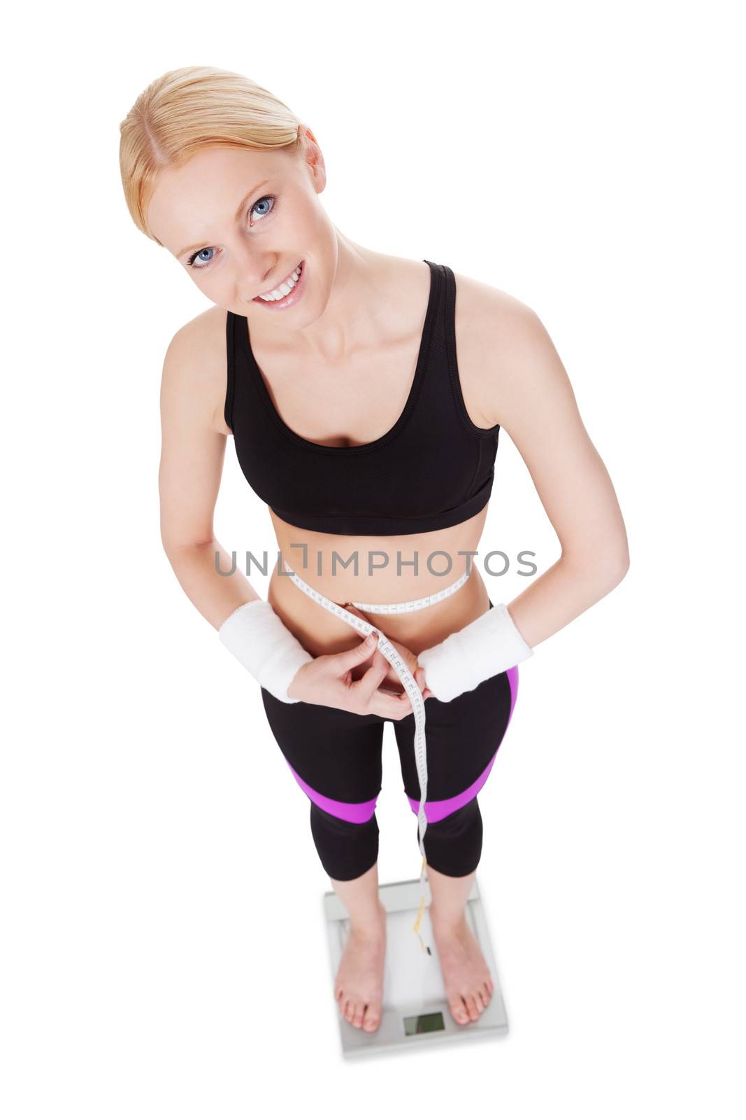 Fitnesswoman standing on weights. Isolated on white