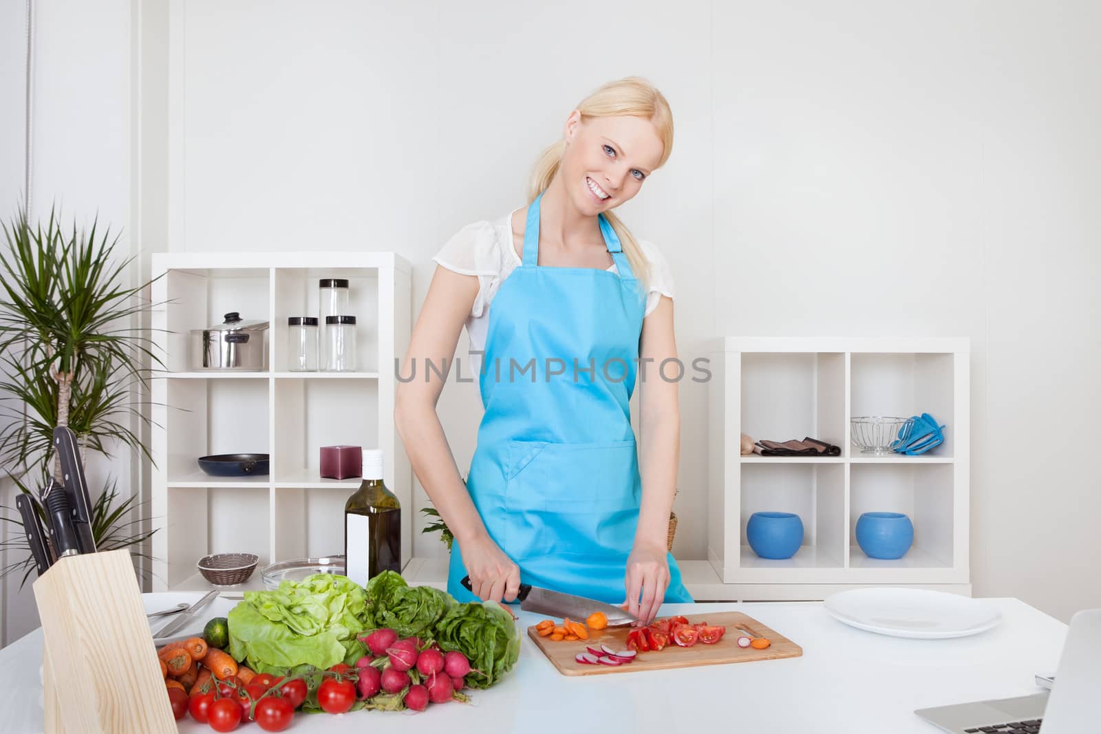 Cheerful young woman cooking in the kitchen