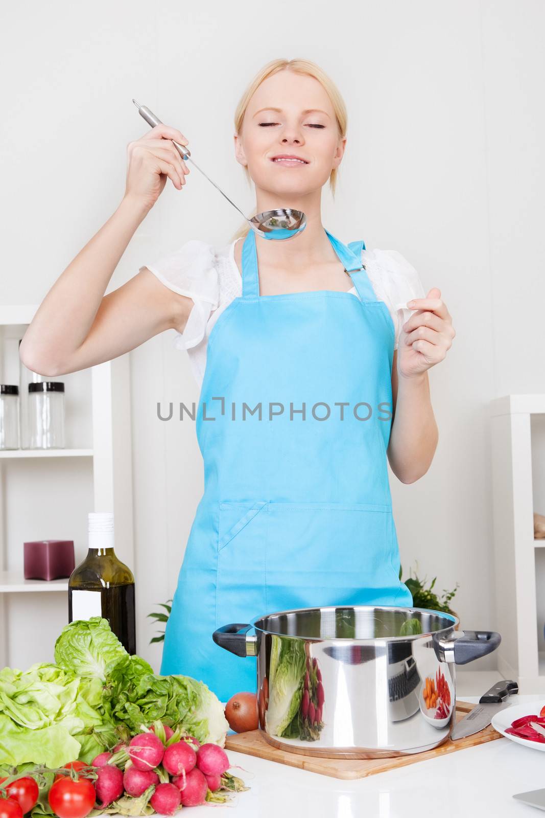 Cheerful young woman cooking in the kitchen