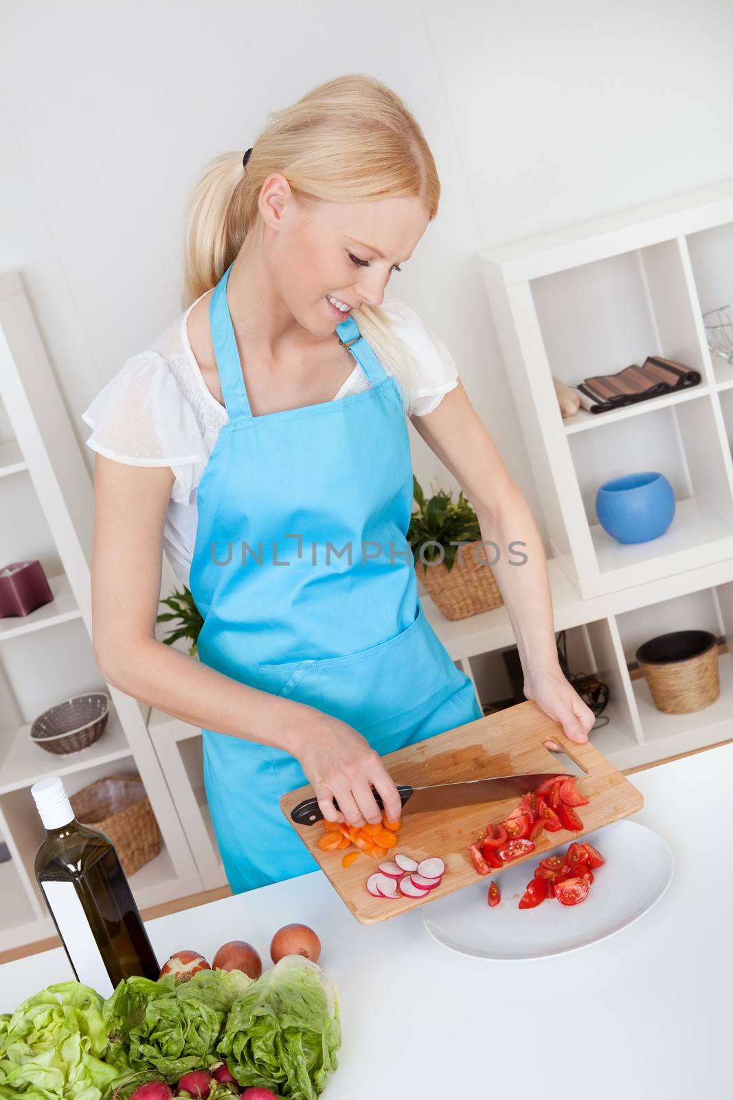 Cheerful young woman cooking in the kitchen