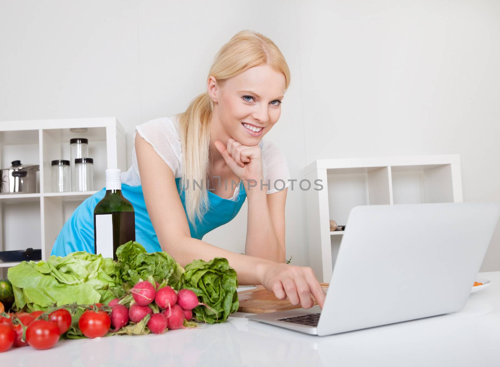 Cheerful young woman cooking in the kitchen