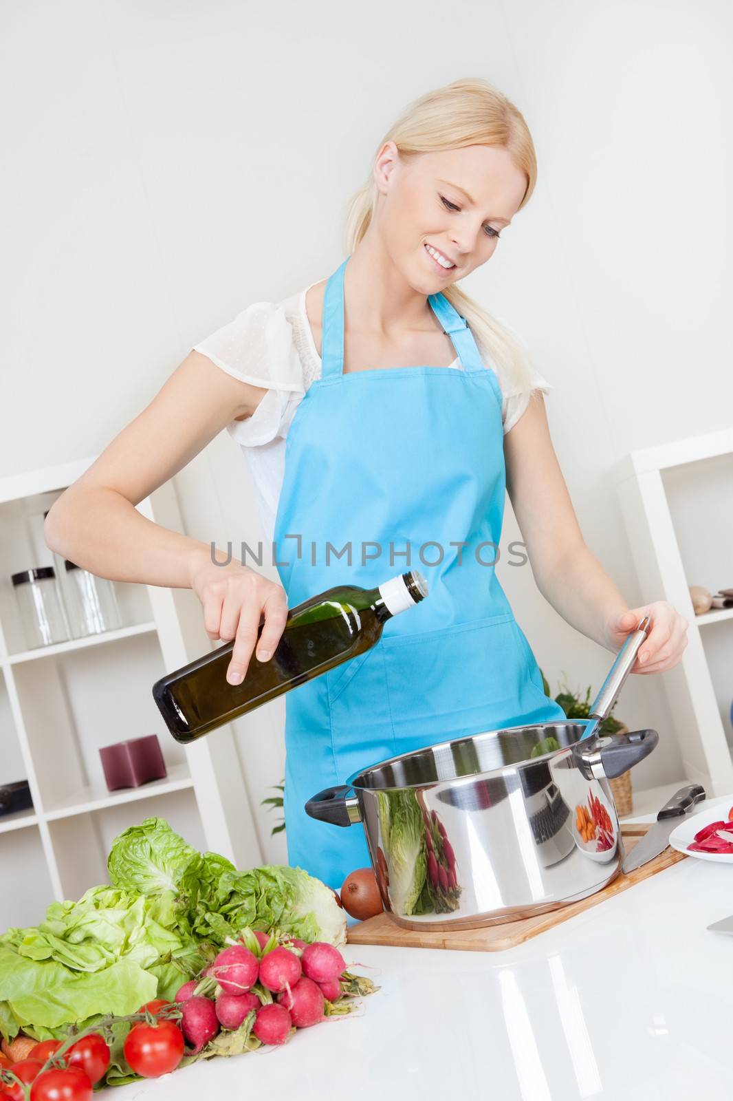 Cheerful young woman cooking in the kitchen