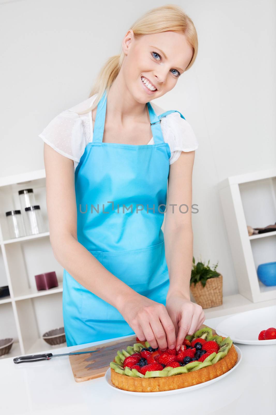 Beautiful young woman making cake in the kitchen