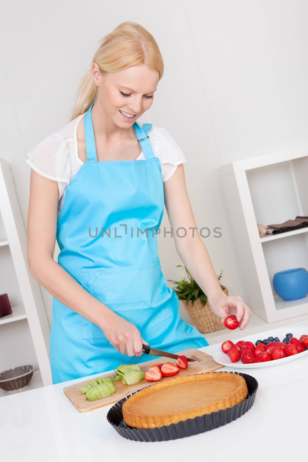 Beautiful young woman making cake in the kitchen